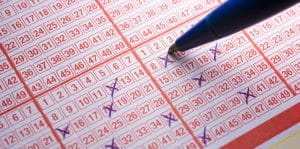 Closeup de o persoană care completează o grilă EuroMillions Lotto Grid